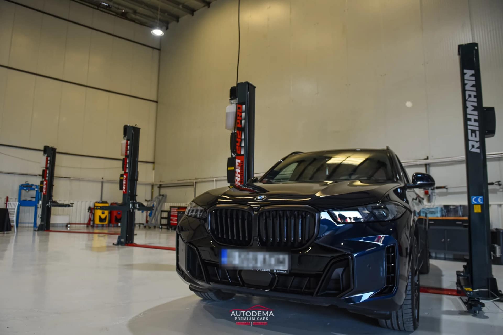 Hala sediului AUTODEMA din Otopeni, cu un SUV între elevatoare cu două coloane
